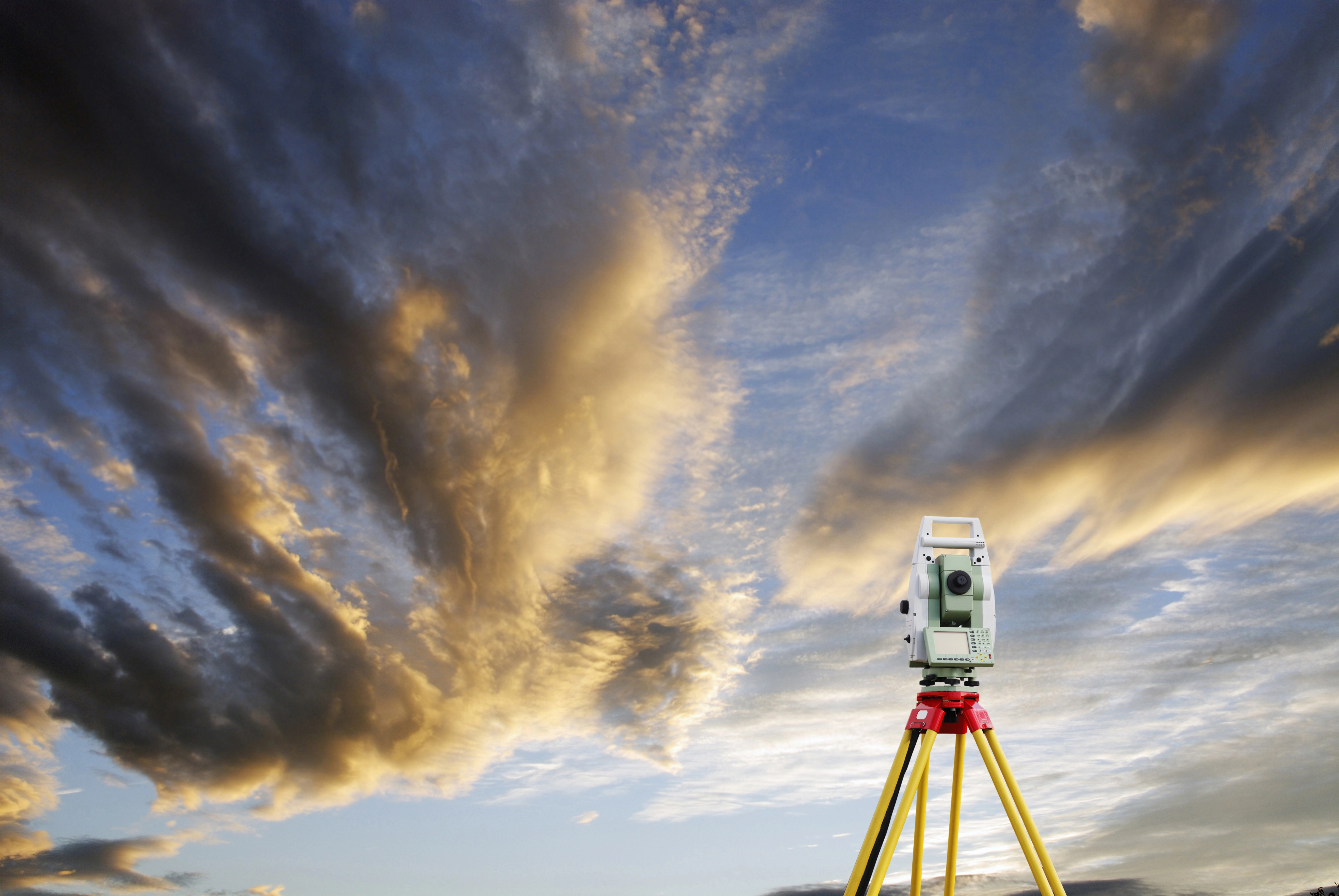 Leica total station on tripod against a dramatic evening sky